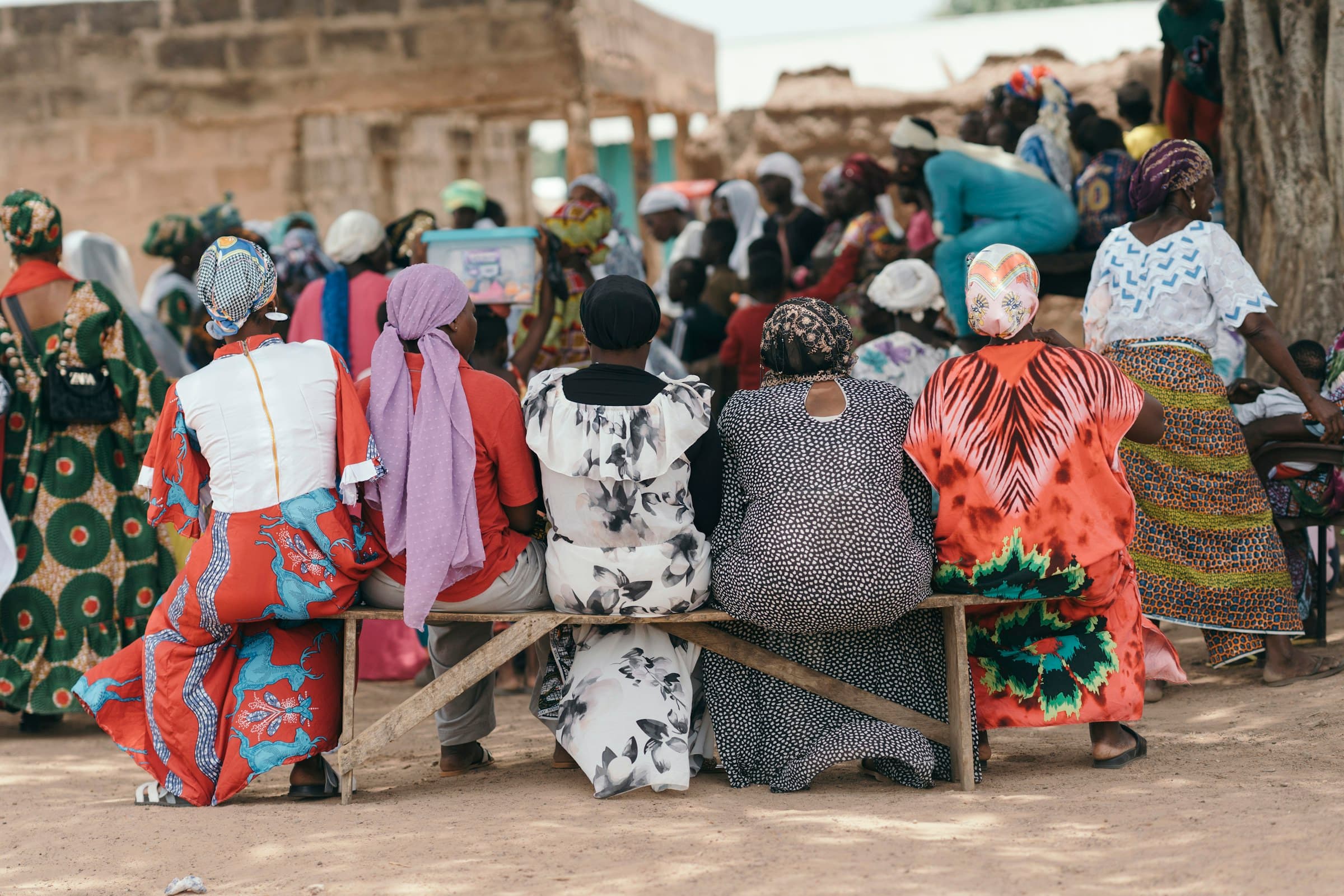 Women seated together on a bench at a community gathering in the Sahel